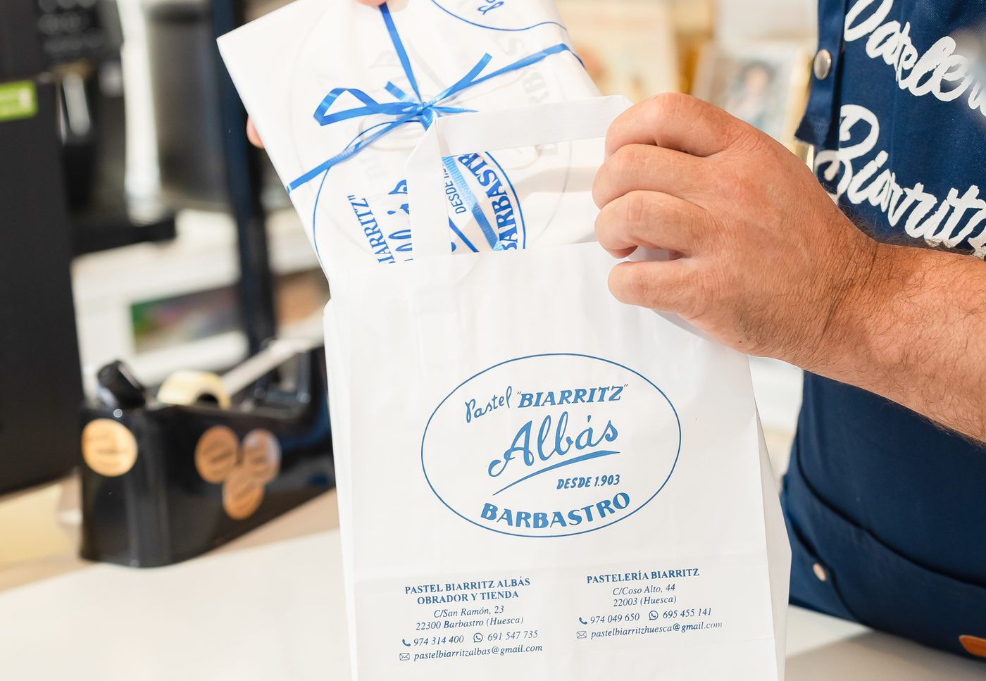 David mete en la bolsa de Albás una caja de Pastel Biarritz atada con lazo azul