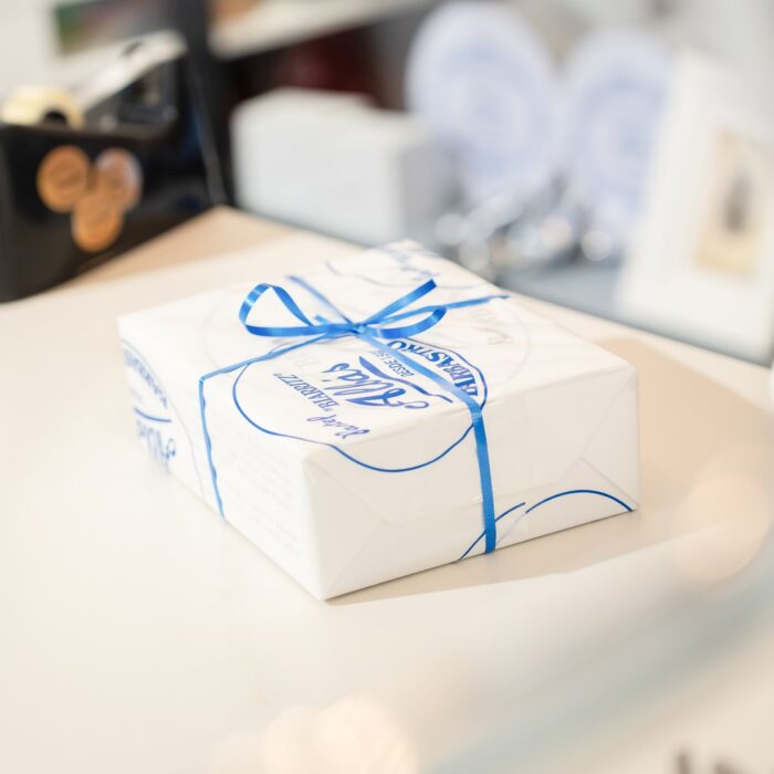 Caja de Pastel Biarritz Albás envuelta con lazo azul sobre el mostrador