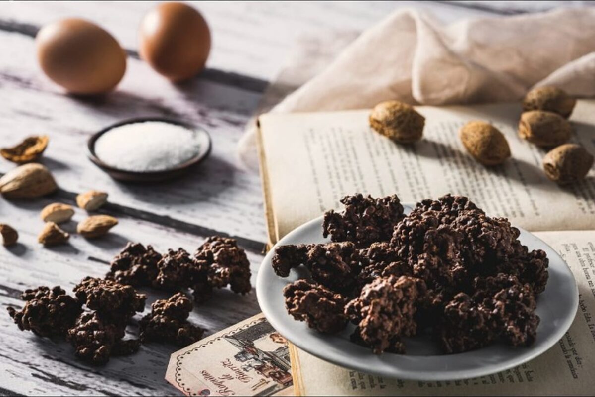 Roquitas de Biarritz en un plato, con almendras, huevos y azúcar sobre un libro antiguo